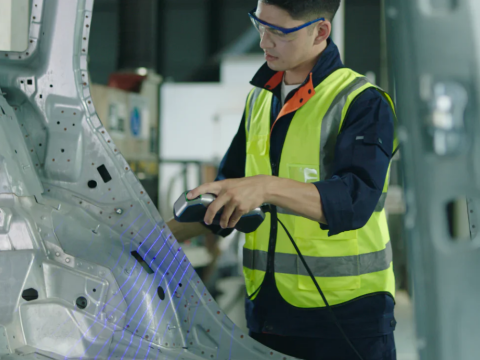 Scanner 3D Revopoint MetroX escaneando com laser azul a carroceria metálica de um carro